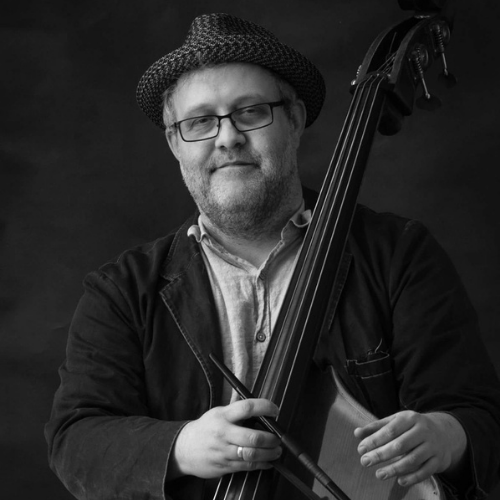 a man with a hat holds a double bass.
