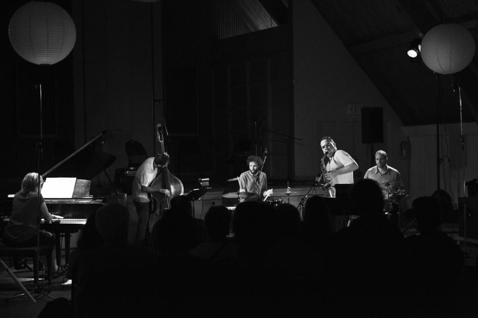 five musicians sit on a stage 