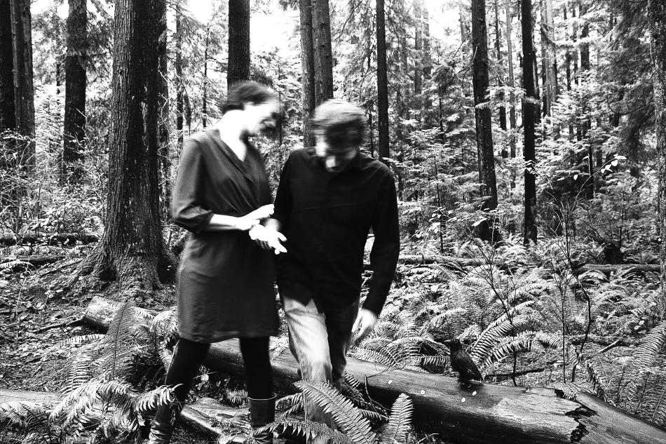 Black and white photo of two people walking through the woods