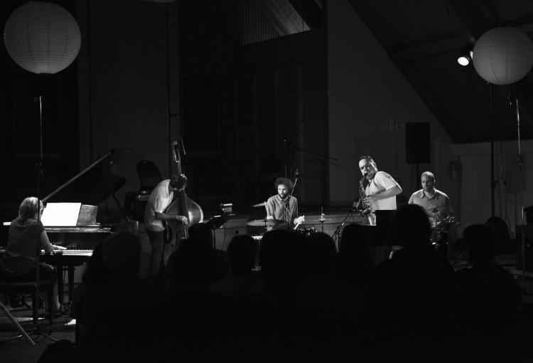 five musicians sit on a stage 